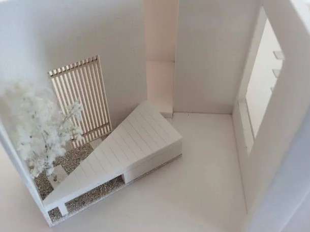 写真は、やまぐち建築設計室が奈良県で手掛けた住宅プロジェクトの空間模型です。敷地の限られた環境において、いかに広がりを感じさせ、心地よい暮らしを実現するかをテーマに設計された一例です。特徴的なのは、斜めに配置されたスロープ状のデッキ。この『斜めの効能』によって、視線が自然に奥へと流れ、物理的な面積以上の奥行き感や開放感を演出しています。さらに、格子を使った目隠しデザインがプライバシーを守りつつ、光や風を取り込む工夫も施されています。限られた敷地条件でも豊かな暮らしを叶える設計術が、この一枚に凝縮されています。