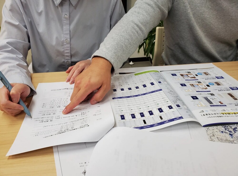 やまぐち建築設計室の打ち合わせ風景。 新築計画中のご夫婦が、生活チェックシートに家事動線・家電・水まわり設備・インテリアの要望を書き出し、暮らしの価値観を整理している様子。間取り設計前の大切なヒアリングとライフスタイルの見直しを行うプロセスを記録した写真。