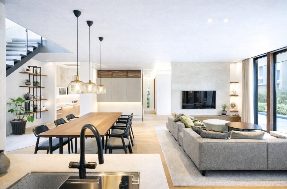 グレー色の天井と明るいナチュラルカラーで統一したホテルライクなLDK空間。ダイニングテーブル周りをすっきり整え、ソファからの視線と生活動線を考慮したレイアウトにより、落ち着く部屋・くつろげる部屋を実現した注文住宅のインテリア事例。家具配置・照明計画・配色バランスまで建築家が設計した住まい。