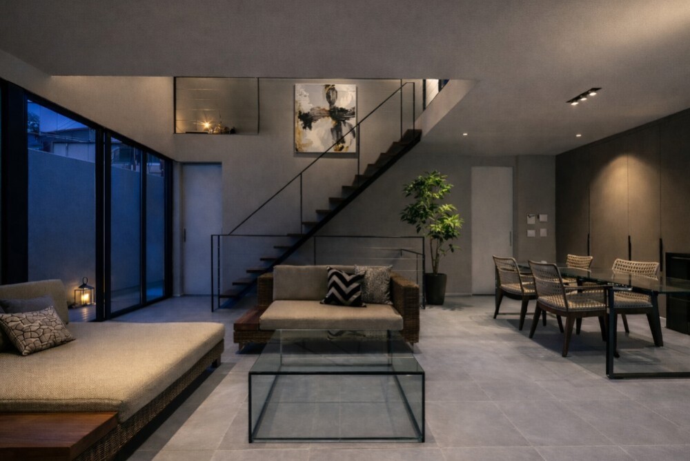 家族それぞれの距離感を大切にした和モダンのデザイナーズ住宅のLDK空間。 薄いグレーのタイル床とガラスのダイニングテーブル・リビングテーブルが、 視線を遮らず、静かな関係性とホテルライクな暮らしを演出している。