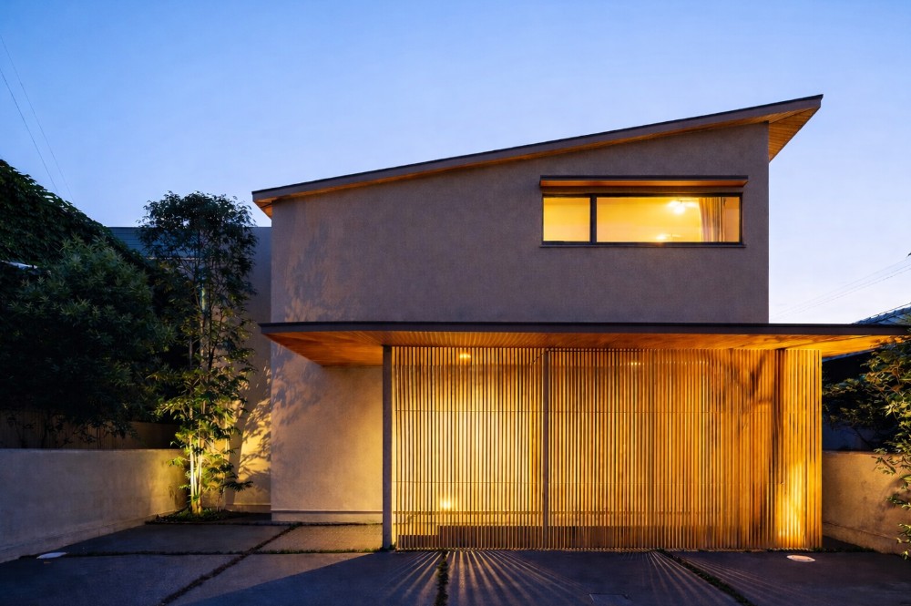 片流れ屋根と800mmの深い軒を備えたモダンでオシャレなデザイナーズ住宅の外観。敷地条件を読み解いた建築家設計により、淡いブラウンの外壁と格子スクリーンが街並みに静かに馴染む。土地の制約を活かし、暮らしの質を高める住まい。