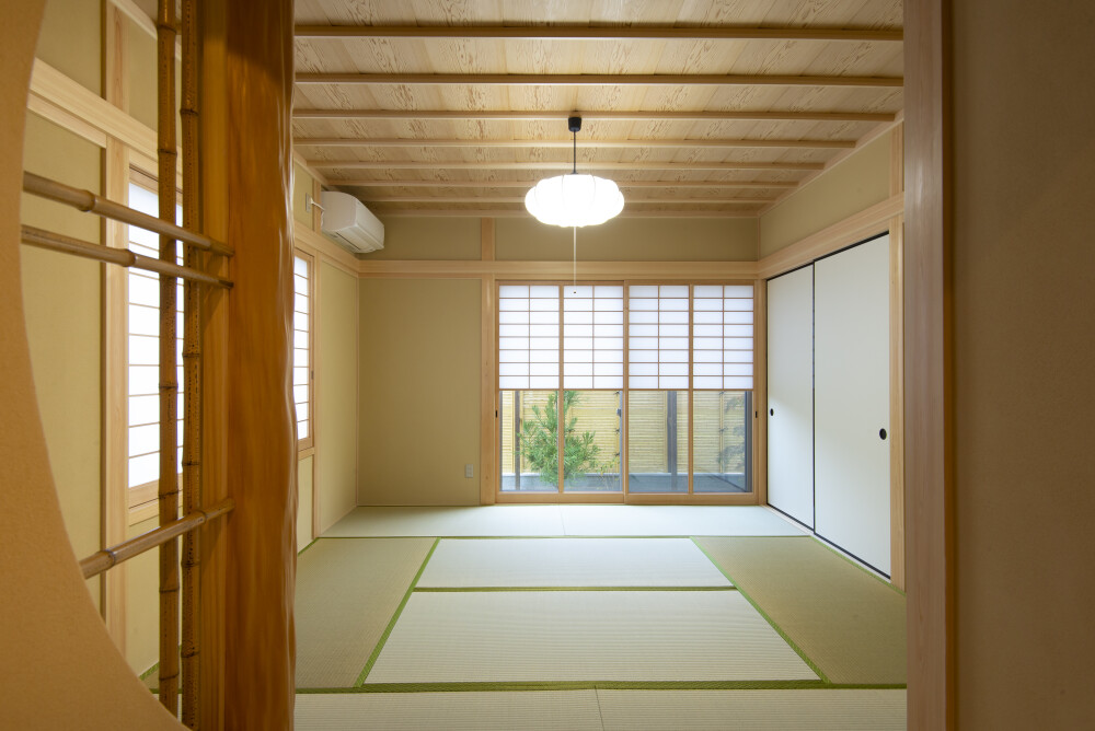 奈良で設計された数寄屋住宅・和風住宅・和モダン住宅の本格和室空間。畳敷きと無垢材の天井、障子越しに庭の緑を取り込む開口部により、光と陰影がやわらかく広がる設計。来客を丁寧にもてなし、日常の中に旅館のような静けさと落ち着きを感じる建築家設計の高級注文住宅。
