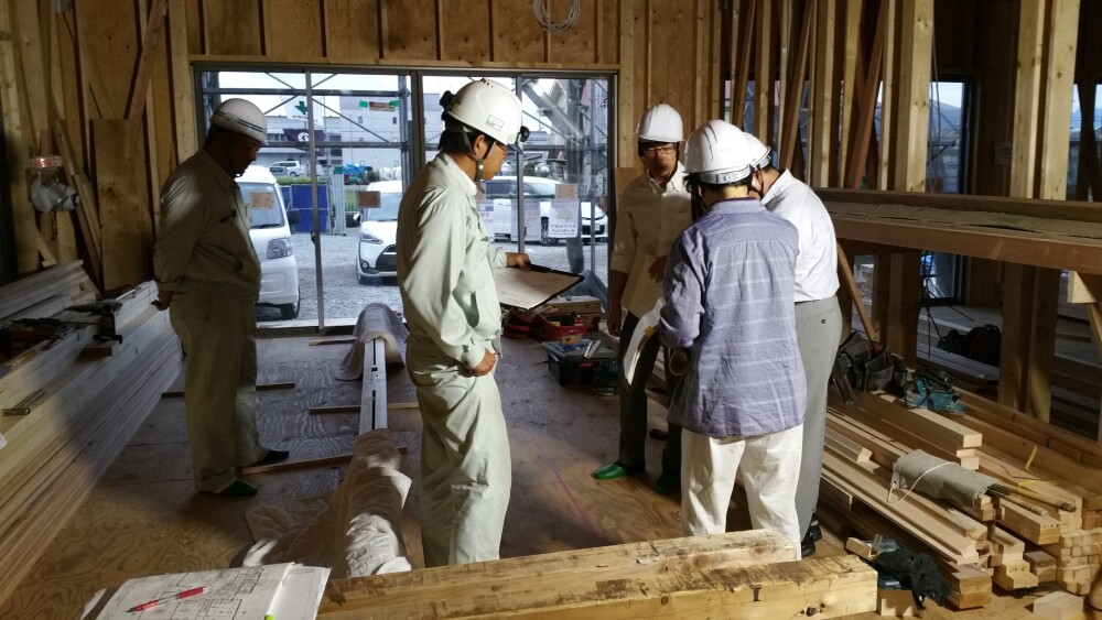 奈良県の注文住宅建築現場で、設計者と工務店、現場監督が図面を確認しながら施工内容や納まりを打ち合わせしている様子。設計監理を通じて断熱性能、防水施工、構造品質、仕上げ精度を確認し、良い工務店と協力しながら住まいの品質を高める家づくりの現場風景。