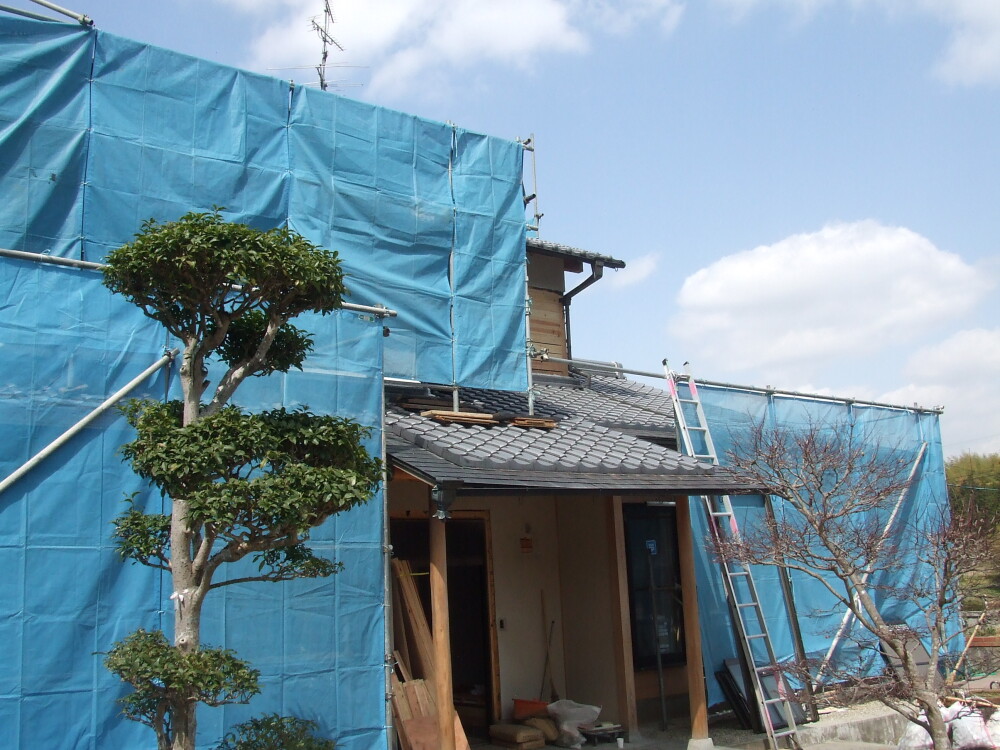 奈良県の中古木造住宅で、足場と養生シートを設置し、屋根や外壁を含む大規模リフォーム工事を進める現場外観