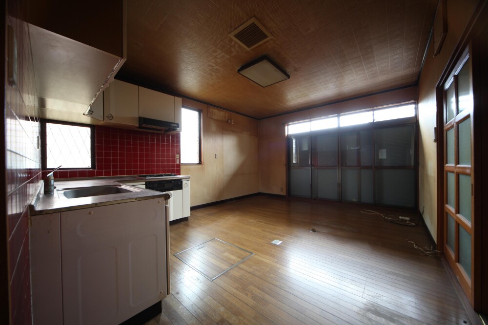 奈良県の戸建て住宅を間取り変更するリフォーム前のLDK。赤いタイル壁の旧キッチンと暗さが残る居間・食堂が一室にあり、採光や家事動線、空間の使いにくさが課題となっていた室内。