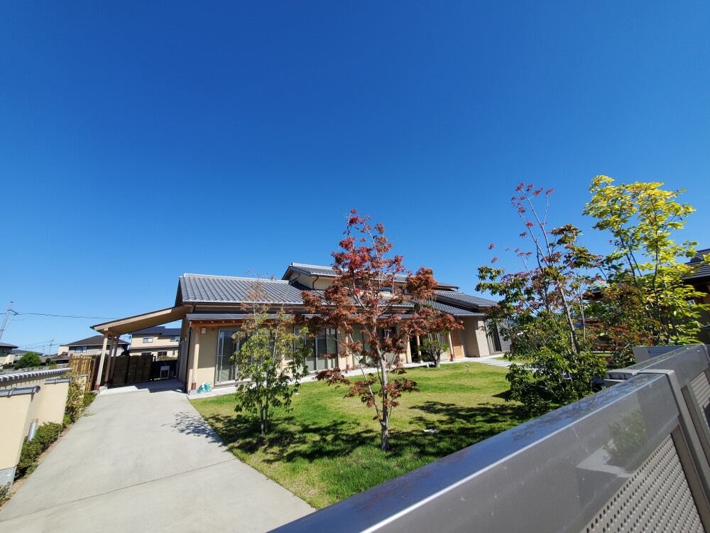 奈良の郊外住宅に設けた芝生と複数の庭木のある広い庭。隣地境界や道路との関係、越境枝、落ち葉、防犯まで考えて庭と外構を管理する住まいの実例。