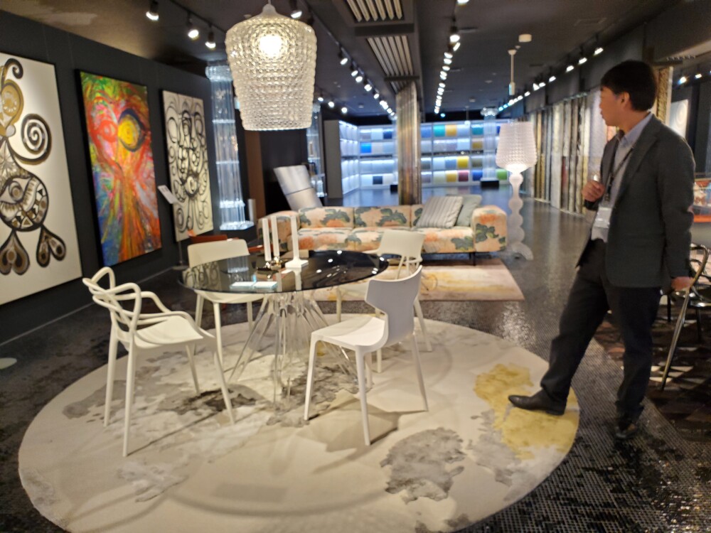 トーヨーキッチンスタイル大阪ショールームで展示されたKartellの家具と照明。透明感のあるテーブルとチェア、アート、ラグ、個性的な照明を組み合わせたインテリアを建築家が確認する様子