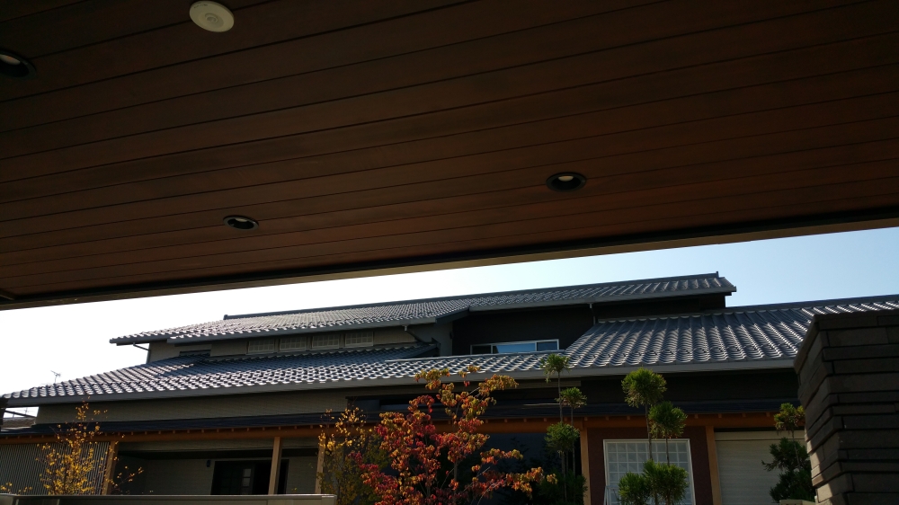 奈良県の高級和モダン住宅の外観ディテール。 深い軒と木目の軒天、瓦屋根の重なりが美しい陰影を生み、植栽と調和した落ち着きある佇まいを演出する建築家設計の注文住宅。