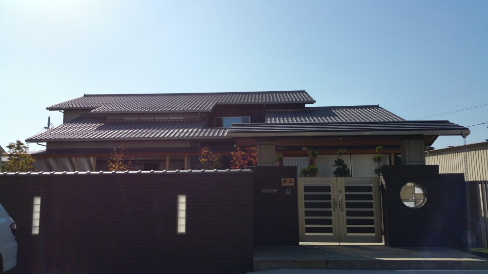 奈良県の高級和モダン住宅の門構え外観。 数寄屋をイメージした塀と重厚なゲート、瓦屋根と植栽が調和し、プライバシーと品格を両立した注文住宅の外構デザイン。